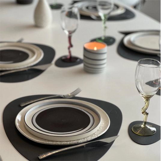 Service en porcelaine dressé sur une table, grandes assiettes blanches Pyrénées et assiettes à entrée noir et blanc Cyclone