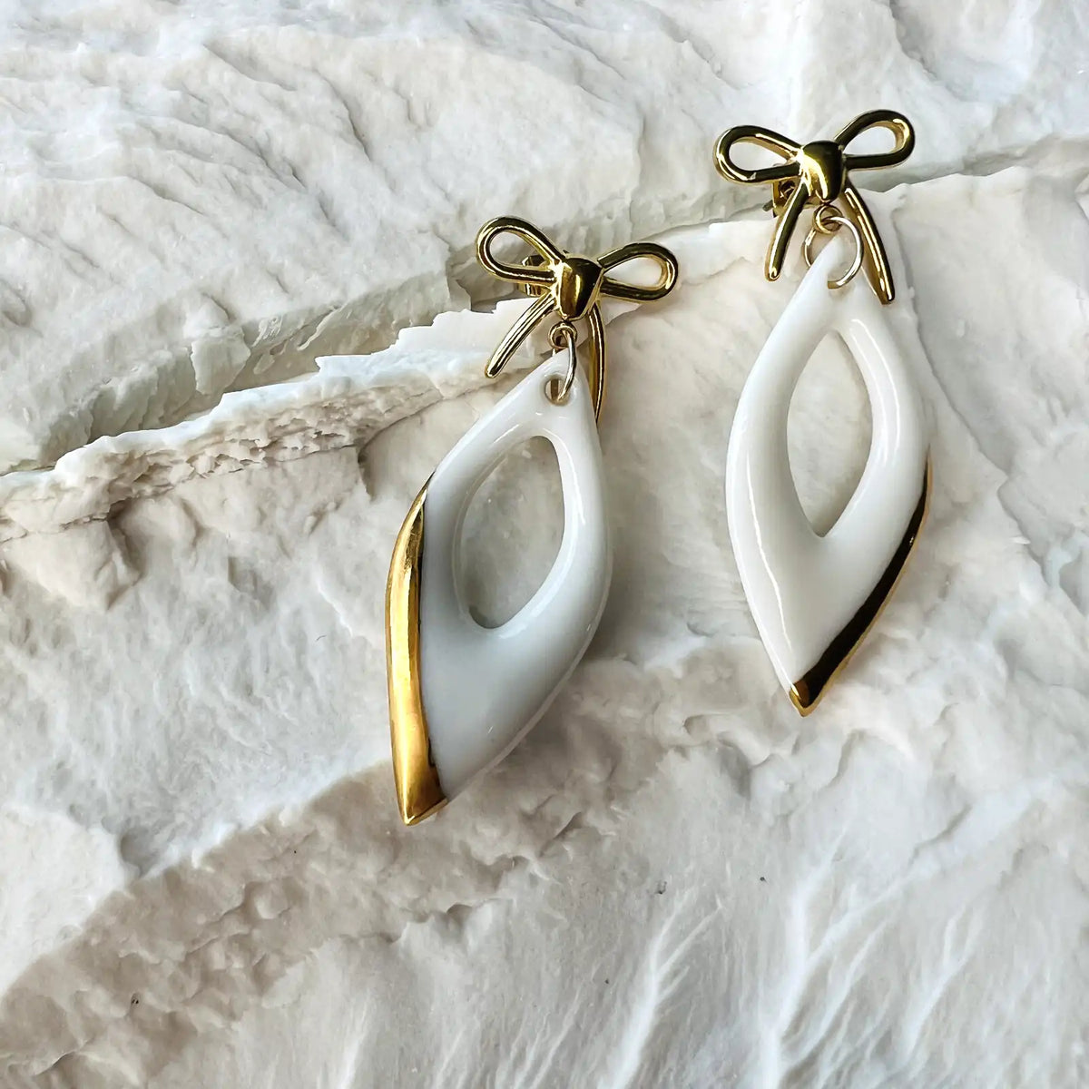 boucles d'oreilles pendantes blanches et dorées avec noeuds