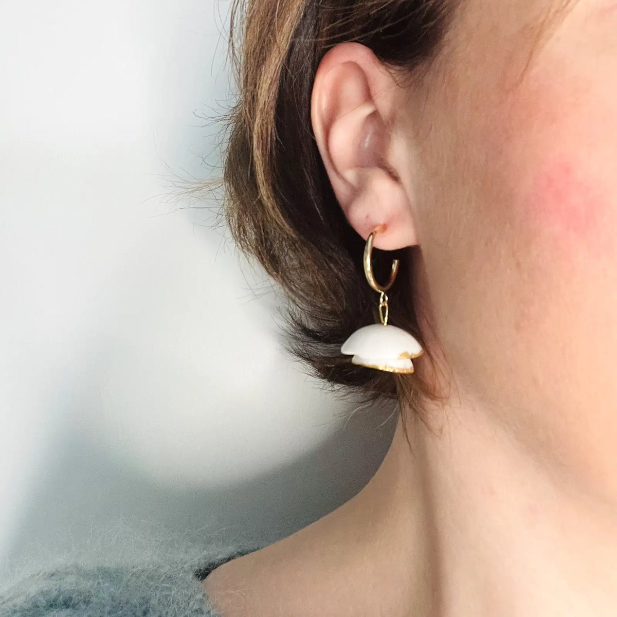 femme portant des boucles d'oreilles blanches et dorées au design floral