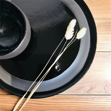Assiette et bol noirs de la collection Basalte vus de dessus, motif circulaire mat tracé sur l'assiette brillante