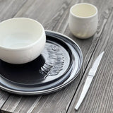 service de vaisselle noir et blanc gravé d'une plume