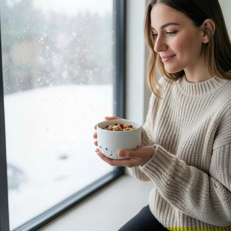 femme prenant son petit déjeuner dans un bol blanc en porcelaine texturé à la main