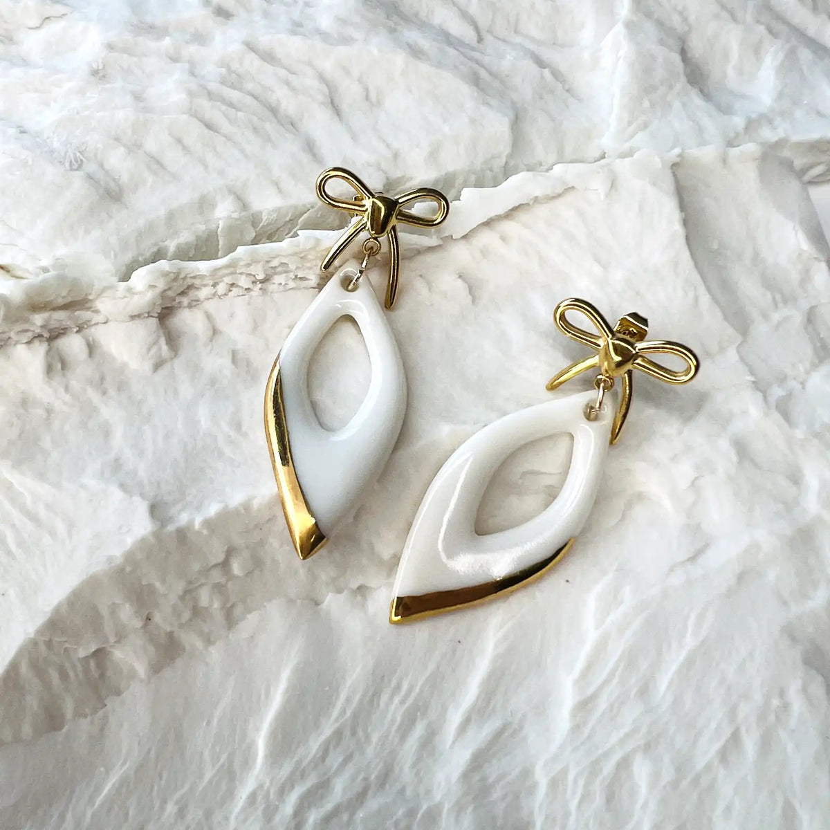 boucles d'oreilles pendantes blanches et dorées avec noeuds