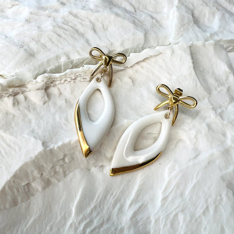 boucles d'oreilles pendantes blanches et dorées avec noeuds