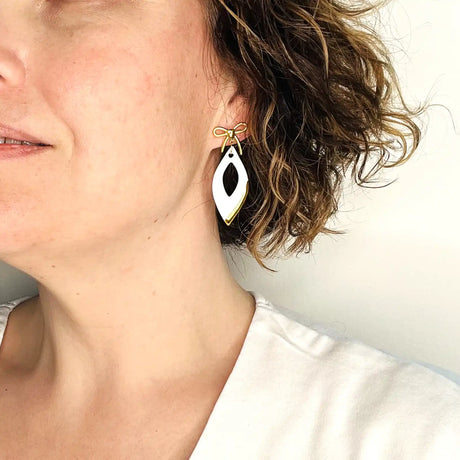 boucles d'oreilles pendantes blanches et dorées avec noeuds