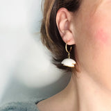 femme portant des boucles d'oreilles blanches et dorées au design floral 
