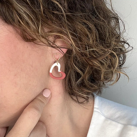 femme portant des boucles d'oreilles à coeur blanc et rouge