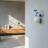 vase mural texturé et ses fleurs bleues en porcelaine sur le mur d'un salon
