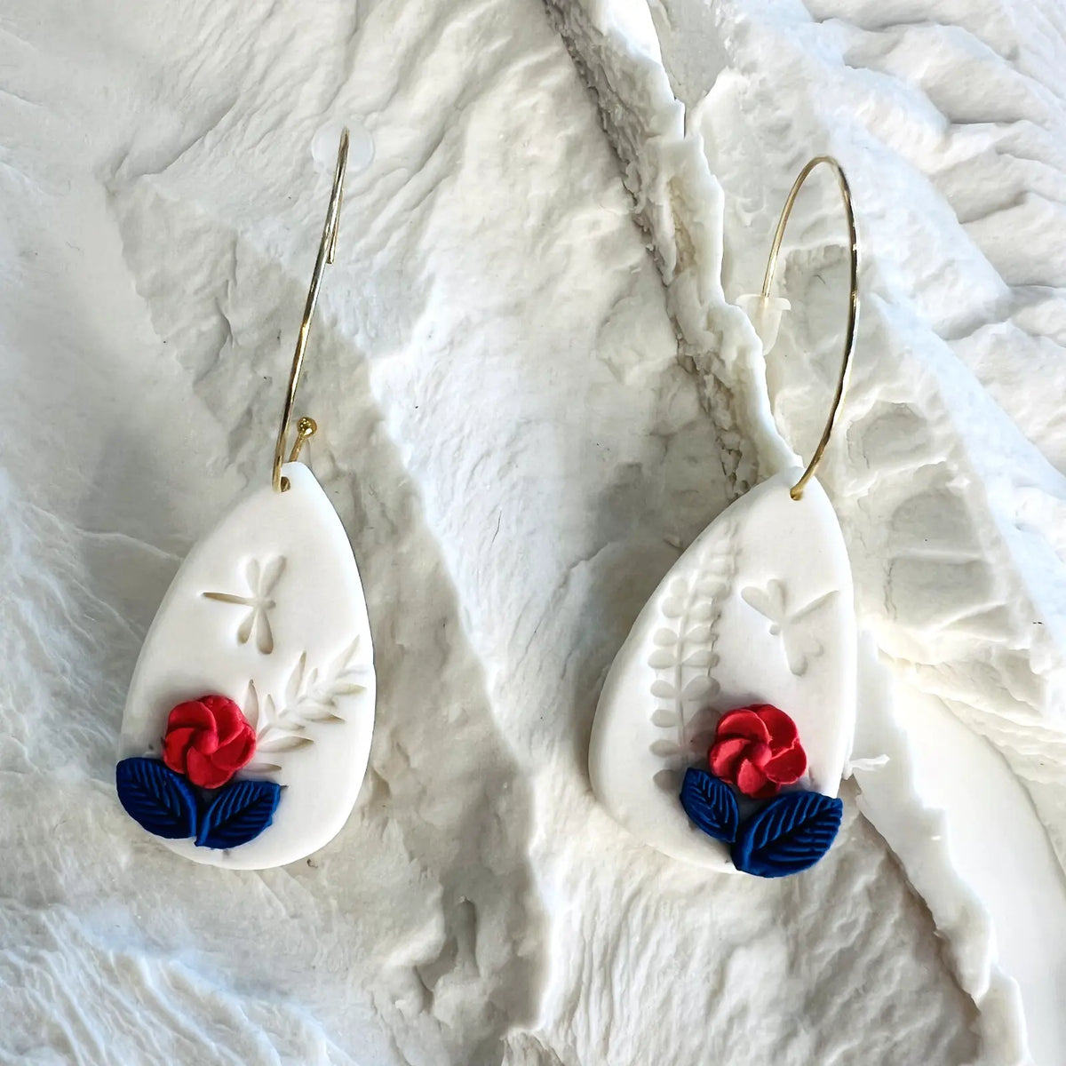 boucles d'oreilles blanches décorées de fleurs rouges et bleues