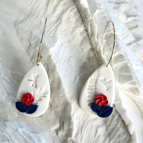 boucles d'oreilles blanches décorées de fleurs rouges et bleues