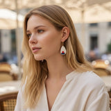 femme portant des boucles d'oreilles blanches décorées de fleurs rouges et bleues