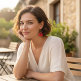 femme portant des boucles d'oreilles rouges décorées de de perles noires