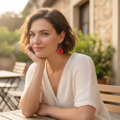 femme portant des boucles d'oreilles rouges décorées de de perles noires