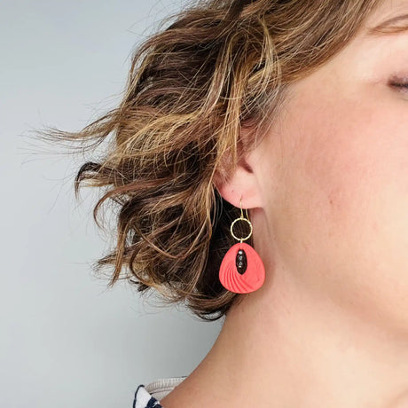 femme portant des boucles d'oreilles rouges décorées de de perles noires