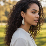 femme potant des boucles d'oreilles en forme de plumes