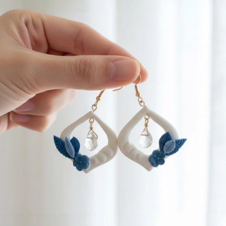 main tenant des boucles d'oreilles blanches et bleues au design floral 