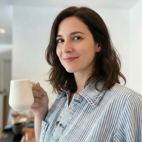 une dame tient un mug noir et blanc gravé d'une plume
