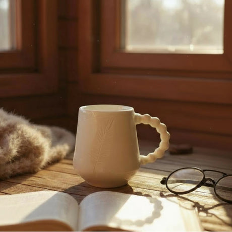 mug blanc gravé d'une plume avec une anse faite d'une assemblage de perles